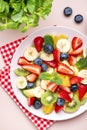 Summer fruit and berry salad with fresh strawberries, blueberries, banana, kiwi, orange and mint, pink background, top view Royalty Free Stock Photo