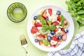 Summer fruit and berry salad with strawberries, blueberries, banana, soft cheese and mint leaves, green background, top view Royalty Free Stock Photo