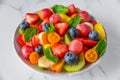 Summer fruit salad in a bowl on white marble background. Healthy diet food for breakfast. Mixed fruits, berries and mint Royalty Free Stock Photo