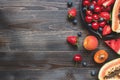 Summer fruits. Fresh juicy berries, watermelon and papaya on the black wooden table, top view.