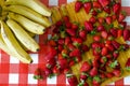 Summer fruits from market, a lot of ripe strawberries and big bunch of yellow bananas Royalty Free Stock Photo