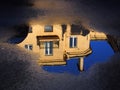 Reflection of a yellow house in a puddle.