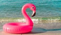 Summer fun beach. Pink inflatable flamingo in blue sea water on summer ocean beach background. Funny bird toy for kids. Royalty Free Stock Photo