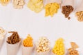 Summer fun fast food - different crunchy snacks in craft paper cornet as decoration border on soft white wood board. Royalty Free Stock Photo