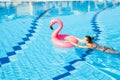 Summer fun. Happy young sexy girl in bikini swimsuit with pink flamingo float in blue pool water. Having fun and Royalty Free Stock Photo