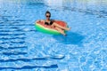 Summer fun. Happy young sexy girl in bikini swimsuit, sunglasses with inflatable rubber ring floating in blue pool water Royalty Free Stock Photo