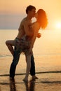 Summer fun holyday on beach background. A loving young couple hugging and kissing on the beach at sunset. Two lovers, man and Royalty Free Stock Photo