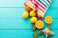 Summer fun time and fruits on blue wooden background. Mock up and picturesque. Orange, lemon, kiwi fruit in bag and shell