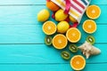 Summer fun time and fruits on blue wooden background. Orange, lemon, kiwi fruit in bag and shell