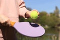 Outdoor sport leisure activity. Hands with a wooden racket and a green ball close-up. Royalty Free Stock Photo