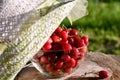 in summer garden glass vase with ripe, juicy cherry is covered with hat on stump. Delicious and healthy food. Royalty Free Stock Photo