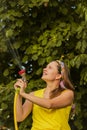 Summer garden, watering - beautiful girl watering roses with garden hose in the garden