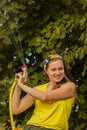 Summer garden, watering - beautiful girl watering roses with garden hose in the garden