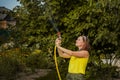 Summer garden, watering - beautiful girl watering roses with garden hose in the garden