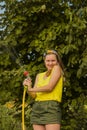 Summer garden, watering - beautiful girl watering roses with garden hose in the garden