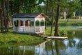 Summer gazebo on shore of pond. Wooden pergola.