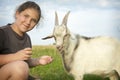 In the summer, a girl feeds a goat in the field Royalty Free Stock Photo