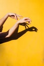 Summer girl teen dancing under direct sun light Minimal happines concept, close up hands silhoutte with shandows yellow background Royalty Free Stock Photo