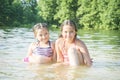 In summer girls sitting in the water are sitting on the lake on a sunny day. They are happy