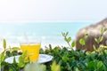 summer, a glass of fresh juice from yellow tropical fruits on the beach, on green grass, against the background of the sea. Royalty Free Stock Photo