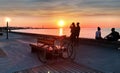 Summer gold sunset sea promenade people walk and relax sea wave sunlight reflection bench and bike on front, tourist travel in T