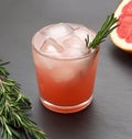 Summer grapefruit cocktail with rosemary and ice on slate background.