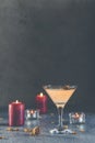 Summer grapefruit martini cocktail with dried roses flowers and petals, surrounded candles on dark gray table surface