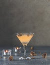 Summer grapefruit martini cocktail with dried roses flowers and petals, surrounded candles on dark gray table surface