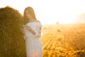 Summer is a great dream time. Beautiful girl in white dress running on the autumn field of wheat at sunset time. Royalty Free Stock Photo