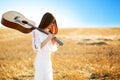 Summer is a great dream time. Beautiful woman with acoustic guitar in field Royalty Free Stock Photo
