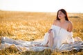 Summer is a great dream time. A young girl in a white dress is walking along the field at sunset. Ripe wheat ears on the Royalty Free Stock Photo