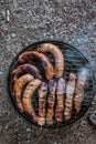 Summer grilling food, sausage, vegetables and kebab meat on barbecue grill over smoke and hot charcoal Royalty Free Stock Photo