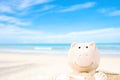 Summer happy piggy bank on sand beach over blurred tropical blue sea background