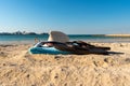 Summer hat, glasses, towel and flip-flops at the sandy beach in front of the blue sea Royalty Free Stock Photo