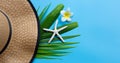 Summer hat with starfish and plumeria or frangipani flower on tropical palm leaves on blue background. Enjoy summer holiday Royalty Free Stock Photo