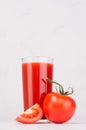 Summer healthy food and drink - pulpy red tomato juice, tomato and juicy piece in light white modern interior, vertical. Royalty Free Stock Photo