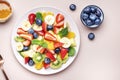 Summer healthy fruit and berry salad with strawberries, blueberries, banana, kiwi, orange and mint leaves, pink background, top Royalty Free Stock Photo