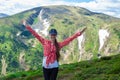 Summer hiking in the mountains. Young tourist girl with long hair in a cap with hands up on the top of the mountains Royalty Free Stock Photo