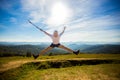 Summer hiking in mountains. Young tourist man in cap with hands up on top of mountains admires nature Royalty Free Stock Photo