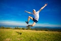 Summer hiking in mountains. Young tourist man in cap with hands up on top of mountains admires nature. Royalty Free Stock Photo