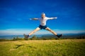 Summer hiking in mountains. Young tourist man in cap with hands up on top of mountains admires nature Royalty Free Stock Photo