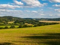 Summer hilly landscape withe green field, forests, blue sky and white clouds