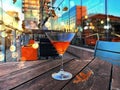 City urban lifestyle glass of orange cocktail on wooden table in street cafe modern buildings and cars traffic night blurred light Royalty Free Stock Photo