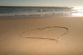 Concept heart handwritten on a sand of beach with wave on background