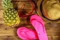 Summer holiday concept. Pineapple, straw hat, flip flops and sunglasses on wooden background Royalty Free Stock Photo