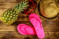 Summer holiday concept. Pineapple, straw hat, flip flops and sunglasses on wooden background Royalty Free Stock Photo