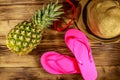 Summer holiday concept. Pineapple, straw hat, flip flops and sunglasses on wooden background Royalty Free Stock Photo