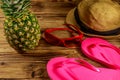 Summer holiday concept. Pineapple, straw hat, flip flops and sunglasses on wooden background Royalty Free Stock Photo