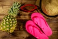 Summer holiday concept. Pineapple, straw hat, flip flops and sunglasses on wooden background Royalty Free Stock Photo