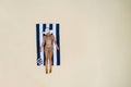 Summer holiday fashion concept - tanning girl wearing sun hat at the beach on a white sand shot from above.Top view from drone.